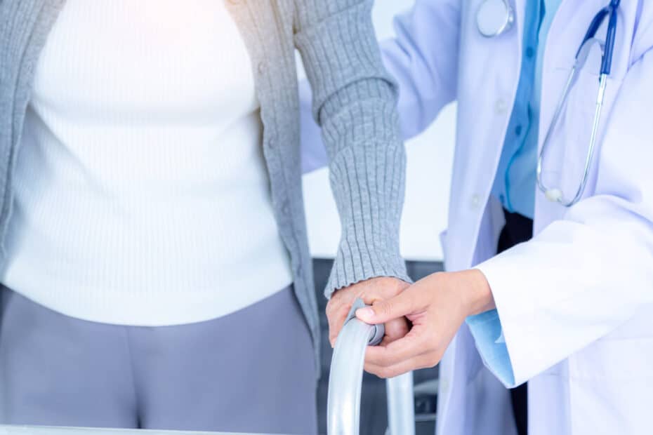 close up female doctor wearing medical mask supporting senior woman by using walker elderly patient care health care medical concept
